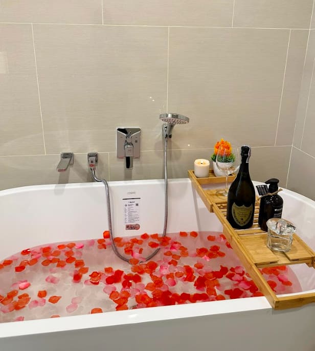 Rose petal bath surrounded by warm lighting